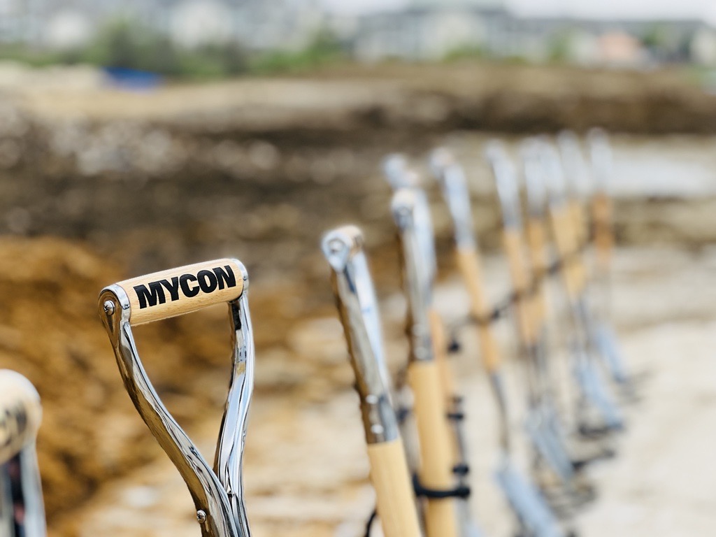 Row of ceremonial shovels at a groundbreaking event.